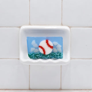 Baseball Vegetable Glycerin Bar Soap in a white soap dish on a tiled bathroom wall