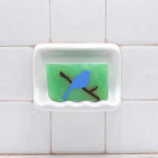 Bluebird Vegetable Glycerin Bar Soap in a white soap dish on a tiled bathroom wall