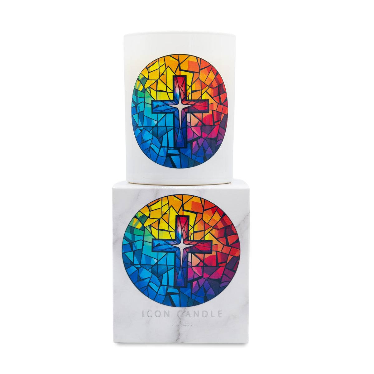 A white wax candle in a cylindrical glass vessel with a colorful stained-glass-style cross design, shown next to its white marble-texture branded box. The design features a vibrant mosaic of red, orange, yellow, green, blue, and purple tones.