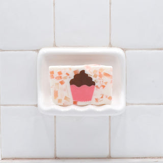 Cupcake Vegetable Glycerin Bar Soap in a white soap dish on a tiled bathroom wall