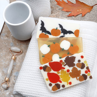 Three soap bars with autumn-themed designs on a towel.