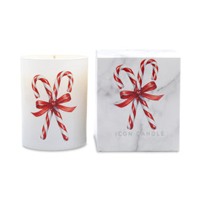 A white candle in a cylindrical glass vessel with a red and white candy cane and red ribbon illustration, shown next to its white marble-patterned box featuring the same design and the text 'ICON CANDLE'.