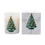 A holiday-themed scented candle in a frosted white glass jar next to its white marble-patterned packaging box. Both feature a green Christmas tree with colorful lights and a gold star on top.