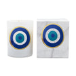 A white glass candle with a blue, teal, and gold concentric target design, shown next to its white marble-patterned box with the same target graphic and the brand name 'ICON CANDLE'.