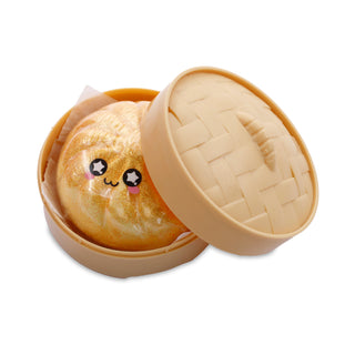A cute, round golden-brown plush toy with a smiling face, packaged in a beige plastic steamer-bowl-style container with a matching lid, isolated on a white background.