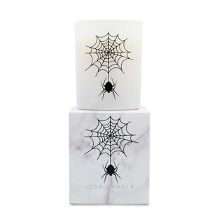 A white glass jar candle with a black spider and cobweb graphic, displayed on top of its matching white marble-patterned box. The box features the brand name 'ICON CANDLE' at the bottom.
