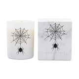 A white candle in a frosted glass jar with a black spider and web graphic, shown next to its white marble-patterned box featuring the same design and the text 'ICON CANDLE'.