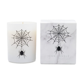 A white candle in a frosted glass jar with a black spider and web graphic, shown next to its white marble-patterned box featuring the same design and the text 'ICON CANDLE'.