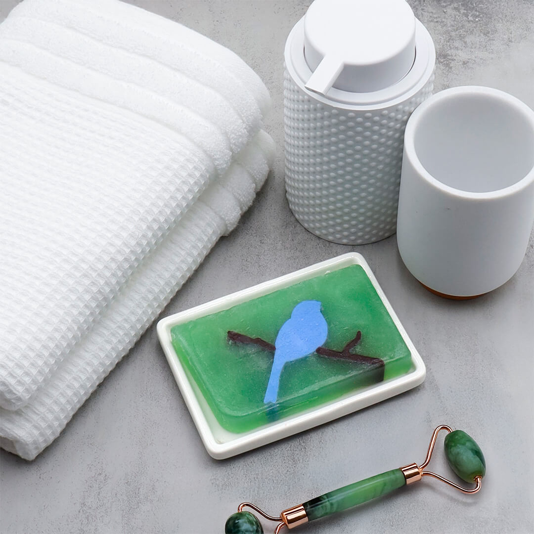 Bluebird glycerin bar soap featuring a soft blue bird perched on a brown branch inside a translucent light green rectangular bar.