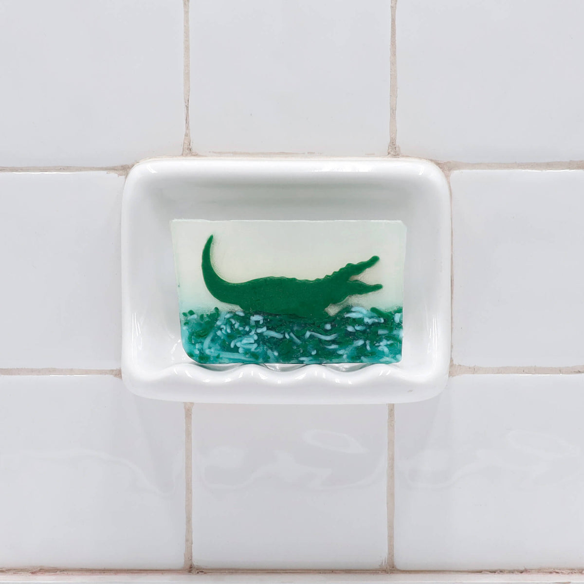 Alligator glycerin bar soap featuring a green alligator suspended in clear soap above textured green swamp-inspired details