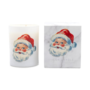A white holiday candle with a vintage-style Santa Claus face illustration next to its white marble-patterned packaging box, both featuring the brand name ICON CANDLE.