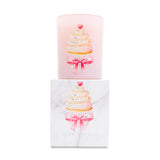 Pink candle with cupcake design and pink bow on top of matching white box on white background