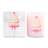 Pink candle with cupcake design and pink bow next to matching white box on white background