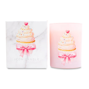 Pink candle with cupcake design and pink bow next to matching white box on white background