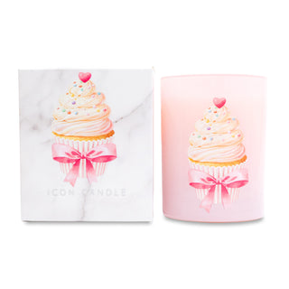 Pink candle with cupcake design and pink bow next to matching white box on white background