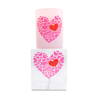 Pink candle with heart design on top of a matching white box on a white background