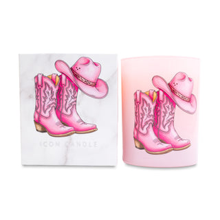 Pink cowboy boots and hat candle next to a matching white box on a white background.