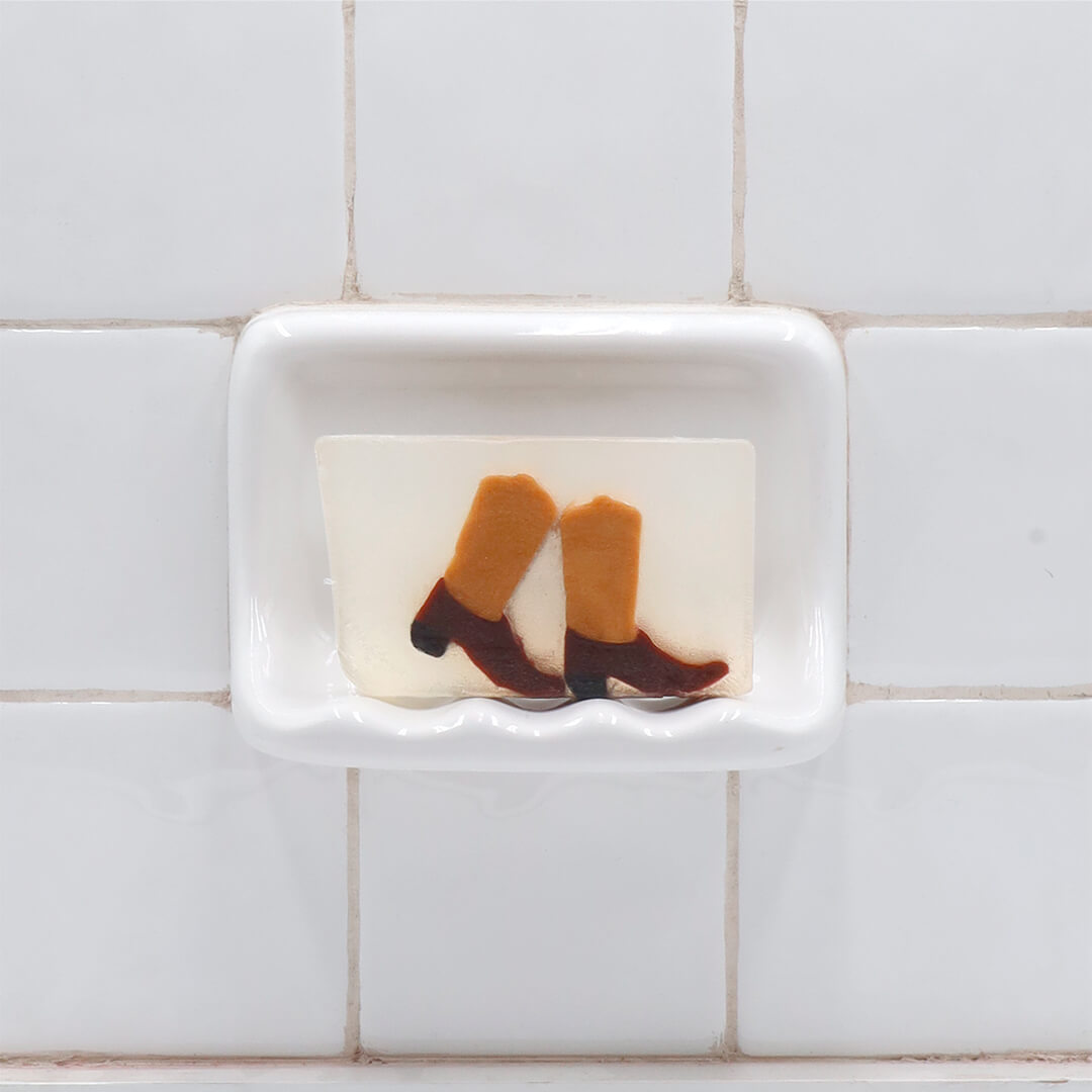 Boots Vegetable Glycerin Bar Soap in a white soap dish on a tiled bathroom wall.