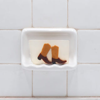 Boots Vegetable Glycerin Bar Soap in a white soap dish on a tiled bathroom wall.