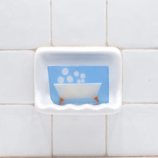 Bubble Bath Vegetable Glycerin Bar Soap in a white soap dish on a tiled bathroom wall.