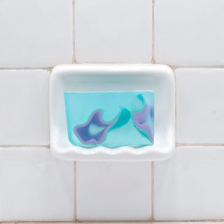 Facets of the Sea Vegetable Glycerin Bar Soap in a white soap dish on a tiled bathroom wall.