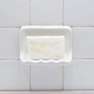 Fiji Coconut Vegetable Glycerin Bar Soap in a white soap dish on a tiled bathroom wall.