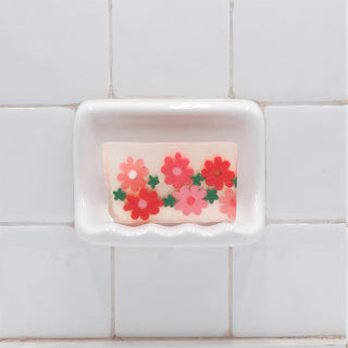 Flowershop Vegetable Glycerin Bar Soap in a white soap dish on a tiled bathroom wall.