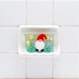 Garden Gnome Vegetable Glycerin Bar Soap in a white soap dish on a tiled bathroom wall.