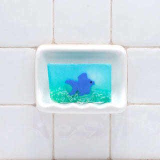 Ginger Fish Vegetable Glycerin Bar Soap in a white soap dish on a tiled bathroom wall.