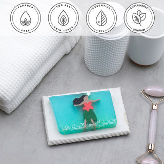 Hula Girl Vegetable Glycerin Bar Soap in a white dish on a stone surface.