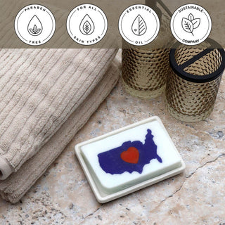 I Heart USA Vegetable Glycerin Bar Soap in a white dish on a stone surface.