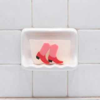 Pink Boots Vegetable Glycerin Bar Soap in a white soap dish on a tiled bathroom wall.
