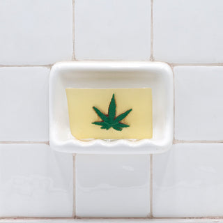Pot Leaf Vegetable Glycerin Bar Soap in a white soap dish on a tiled bathroom wall.