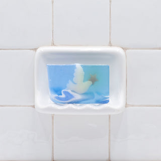Skyward Vegetable Glycerin Bar Soap in a white soap dish on a tiled bathroom wall.