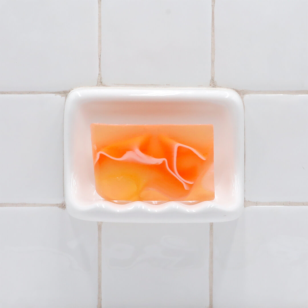 Tomato Juice Complexion Vegetable Glycerin Bar Soap in a white soap dish on a tiled bathroom wall.
