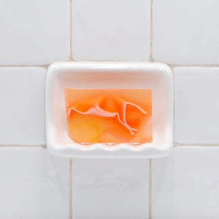 Tomato Juice Complexion Vegetable Glycerin Bar Soap in a white soap dish on a tiled bathroom wall.