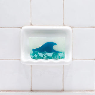 Tranquility Vegetable Glycerin Bar Soap in a white soap dish on a tiled bathroom wall.