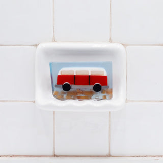 Wanderlust Vegetable Glycerin Bar Soap in a white soap dish on a tiled bathroom wall.